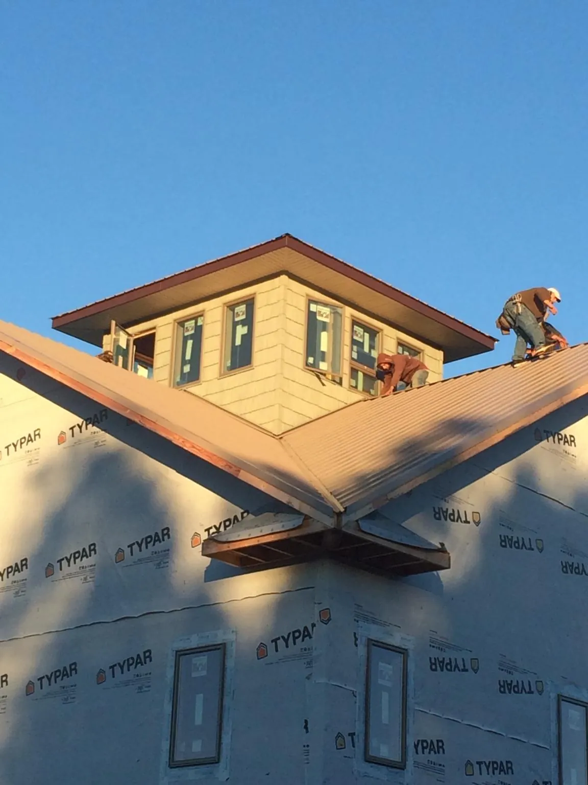 Roofers working around a rooftop cupola on a new metal roof at sunset — Roof Waterproofing in Glenville by Roofing Brothers